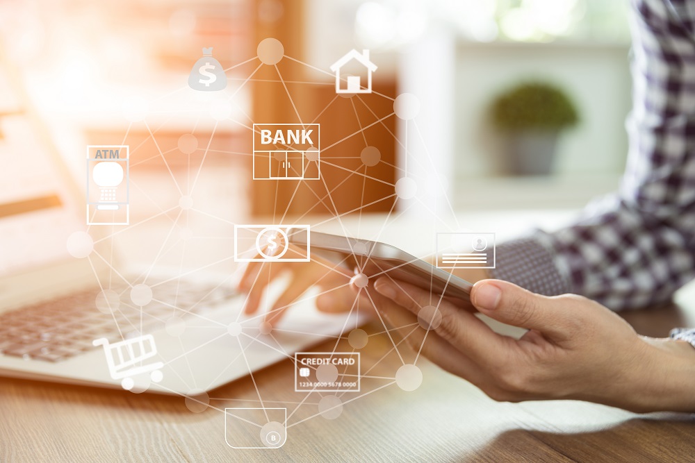 person on phone and laptop with bank items around