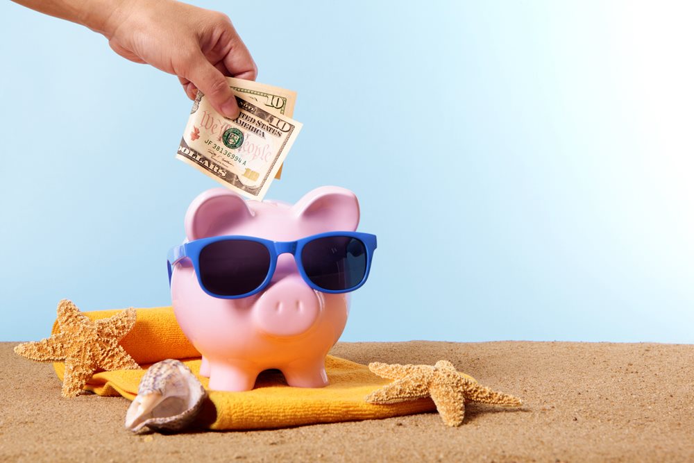 Piggy bank wearing glasses sitting on a beach 