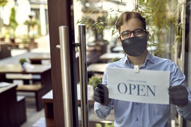 small business owner with reopening sign