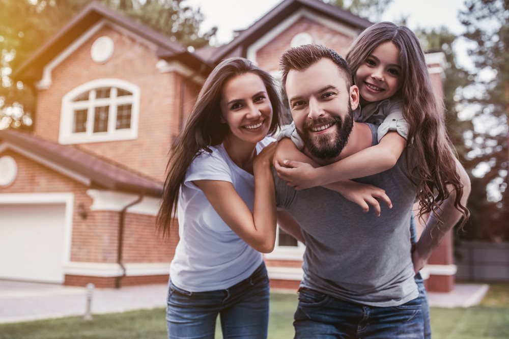 Family smiling outside of new house